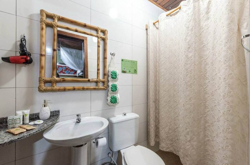 Bathroom with a bamboo-framed mirror, a pedestal sink and a shower curtain
