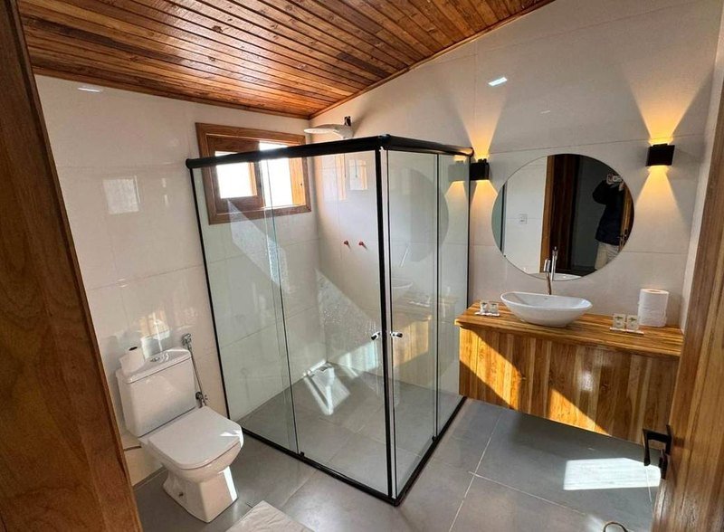 Bathroom with a glass shower, a round mirror and a wooden vanity with a basin