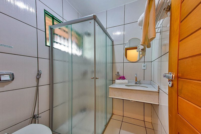 Bathroom with a glass shower enclosure, a sink on a marble counter, a round mirror and towels