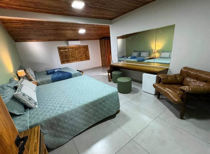 Bedroom with beds in green and blue linen, a desk and a leather armchair