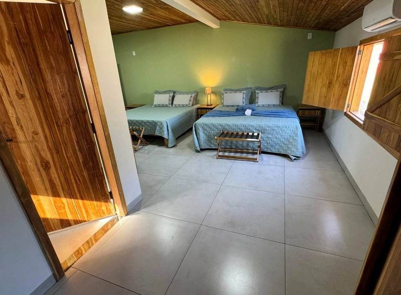 Bedroom with two beds, a wooden door and a window with wooden shutters