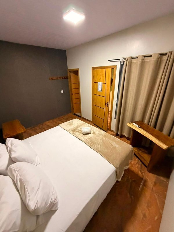 Apartment with a double bed, wooden doors, a curtain and a wooden side table