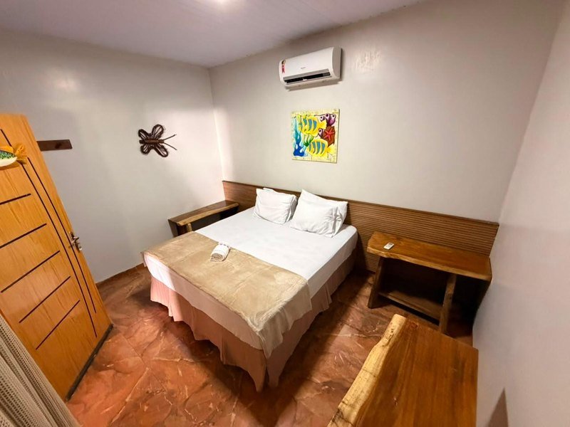 Apartment with a double bed, a folded towel, wooden side tables, an air conditioner and a colorful fish painting