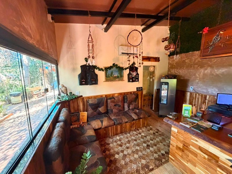 Reception lounge with a long sofa, a patterned rug, dreamcatchers, a reception counter and a glass wall facing the garden