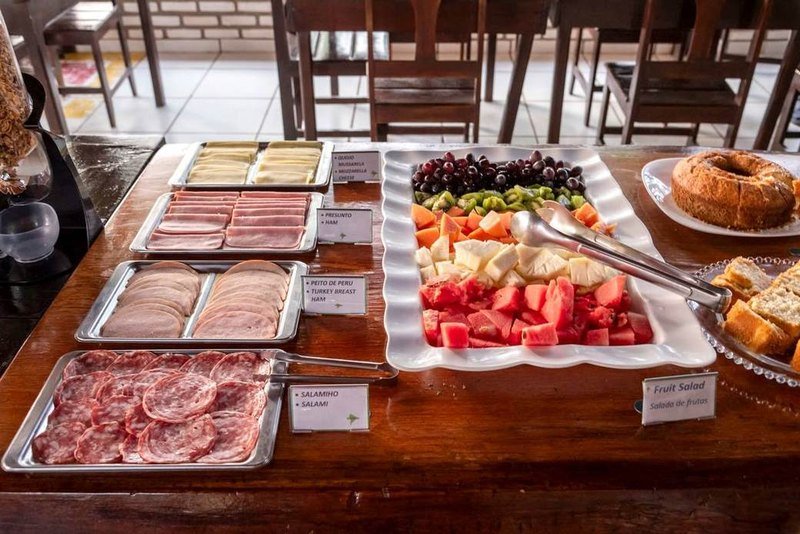 Breakfast buffet with sliced cold cuts, cheese, fruit salad and cakes on a wooden table