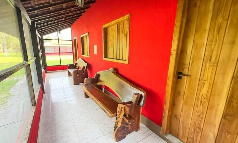 Covered veranda with a carved wooden bench along a red wall and a wooden door
