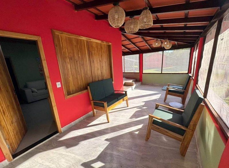 Covered veranda with wooden armchairs, red walls and a door to the living room