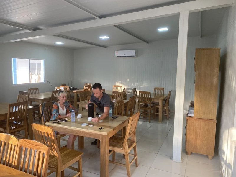 Dining room with wooden tables and chairs, where two guests are having coffee