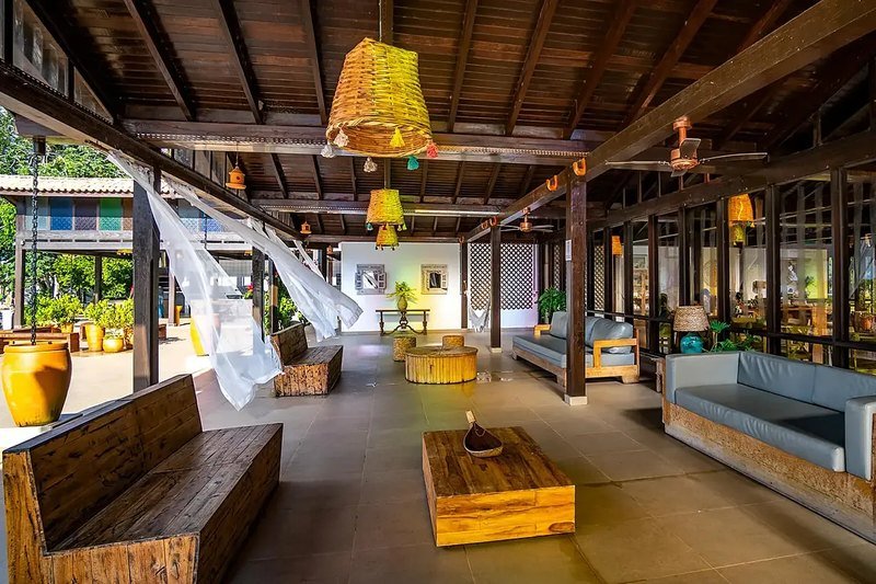 Open-air lounge with wooden benches and sofas, woven pendant lamps and ceiling fans under a wooden roof