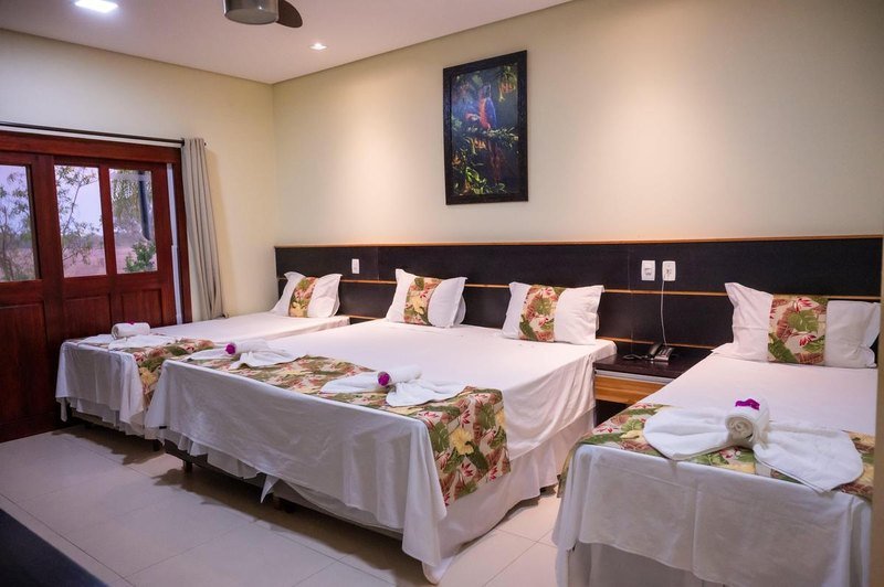 Suíte Luxo bedroom with three beds, a framed painting and wooden doors