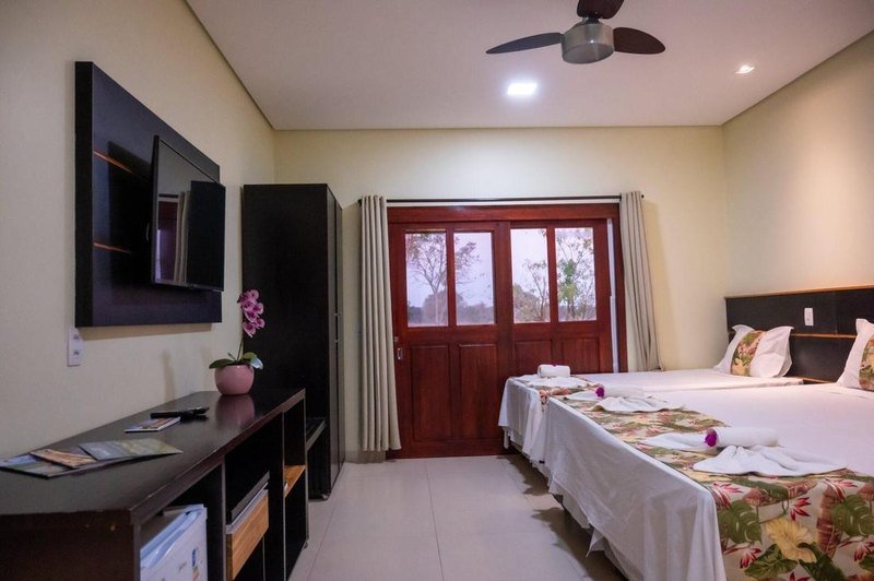 Suíte Luxo with a wall-mounted TV, a wardrobe and wooden double doors