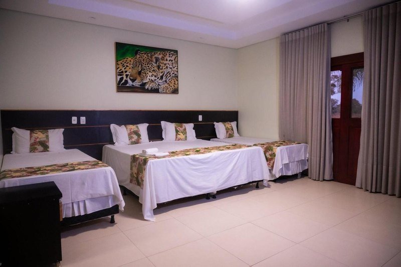 Suíte Master bedroom with three beds and a framed jaguar painting